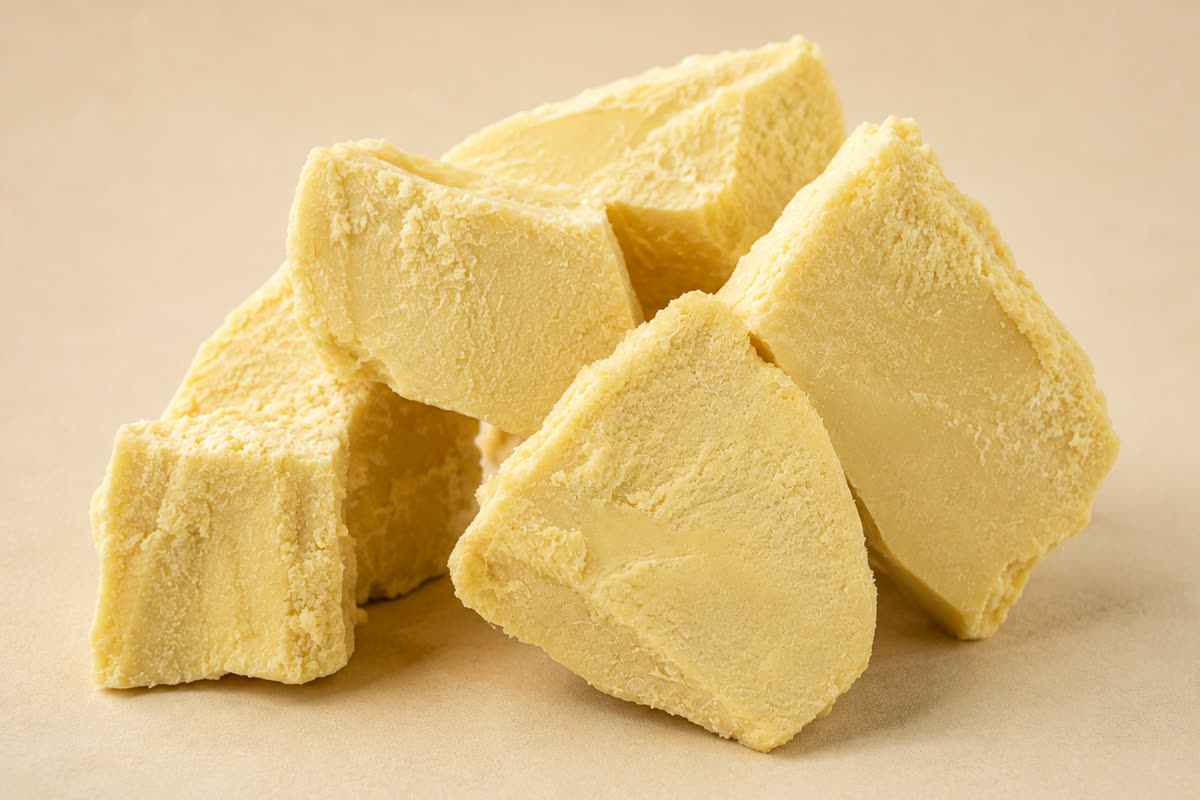 Chunks of raw unrefined shea butter, showing the pale yellow colour and crumbly cut surface