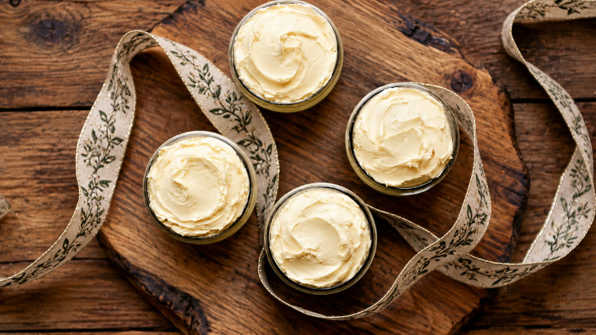 Four jars of whipped body butter, cooling on a wooden board